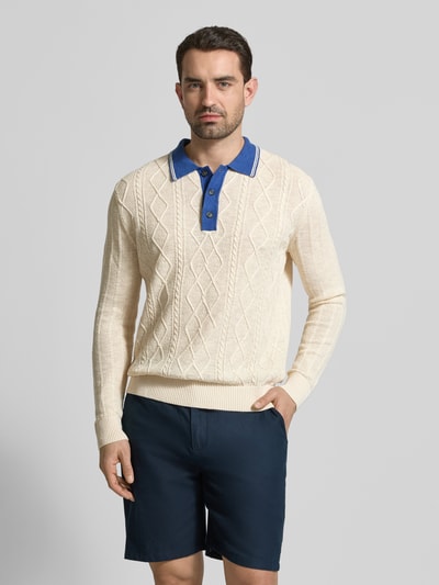 Męskamodel nosi Strickpullover aus Leinen-Mix mit Polokragen von Gant, kremowy sweter z fakturą, krój slim fit, granatowy kołnierzyk, długość tyłu 68 cm, długość rękawa 70 cm, widok całej sylwetki z przodu.