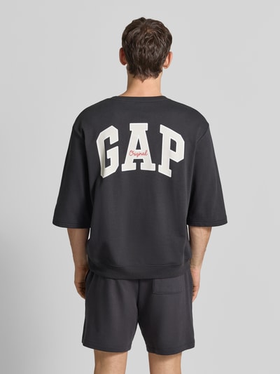 Männermodel trägt T-Shirt mit ronde hals en logoprint van GAP, katoenmix, loose fit, ribboorden, ruglengte maat M 70 cm, rugaanzicht