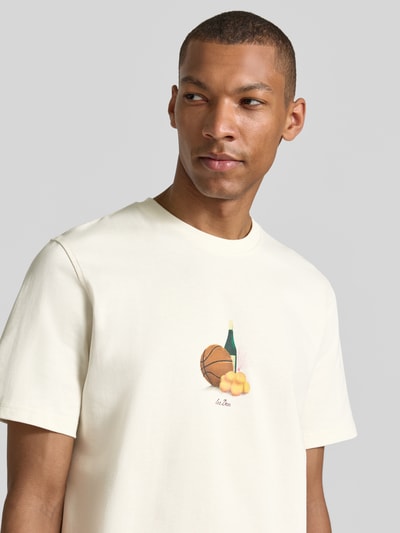 Männermodel trägt T-Shirt mit Label-Detail von Les Deux in Creme, Reine Baumwolle, Gerader-Schnitt, Rundhalsausschnitt, Nahaufnahme Oberkörper. Rückenlänge bei Größe M: 65 cm.