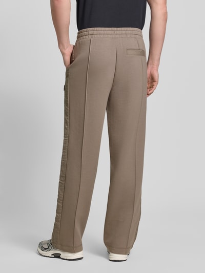 Männermodel trägt Comfort Fit Sweatpants aus Baumwoll-Mix Modell 'DROSPANT' von HUGO in Beige, Lochstick-Einsatz, Rückansicht Ganzkörperansicht.
