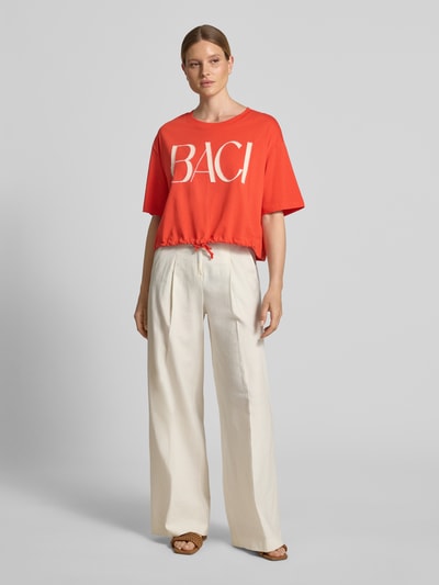 Frauenmodel trägt Boxy Fit T-Shirt mit Perlen und Tunnelzug von Oui aus Baumwoll-Elasthan-Mix in Orange, Rundhalsausschnitt, Ganzkörperansicht von vorne.
