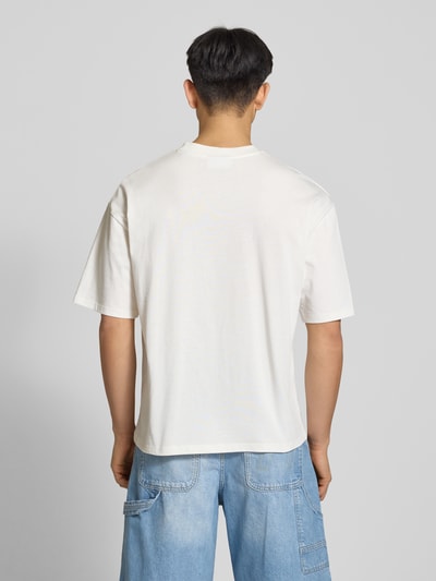 Männermodel trägt T-Shirt mit Logo- und Statement-Stitching von REVIEW aus reiner Baumwolle in Weiß, gerader Schnitt, Rückansicht Ganzkörperansicht.