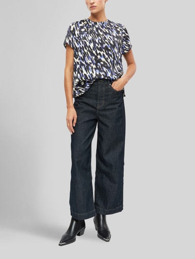 Kobiece model prezentuje bluzkę z krótkim rękawem Regular Fit Kurzarmbluse mit Falten-Detail von s.Oliver BLACK LABEL, wzór w odcieniach niebieskiego, czerni i bieli, szerokie ciemne jeansy, czarne buty, zdjęcie całej sylwetki z przodu, damska bluzka z krótkim rękawem od s.Oliver BLACK LABEL