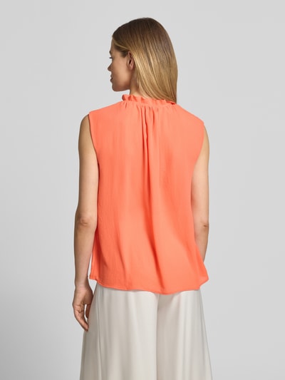Frauenmodel trägt Blusenshirt mit Rüschen und Kappärmeln von Marc Cain in Koralle, gerader Schnitt, fließende Textur, Ganzkörperansicht Rückansicht. Rückenlänge bei Größe 36: 63 cm, Label-Detail erkennbar.