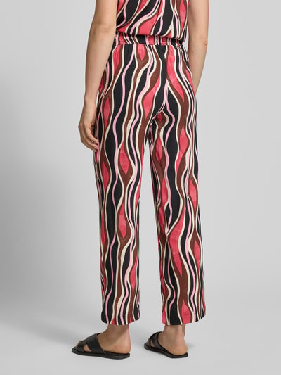 Frauenmodel trägt Straight Fit Stoffhose aus reiner Viskose Modell 'Cammi' von Soyaconcept mit abstraktem Muster, Ganzkörperansicht Rückansicht, Damen Stoffhose, Elastischer Bund mit Tunnelzug, Bundweite bei Größe S 35 cm, Innenbeinlänge bei Größe S 74 cm.