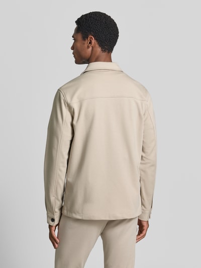 Männermodel trägt Slim Fit Hemdjacke mit Viskose-Anteil von Lindbergh in Beige, glatte Textur, Rückenansicht, Ganzkörperansicht Rückansicht. Rückenlänge bei Größe M: 70 cm, elastischer Material-Mix, Umlegekragen, durchgehende Knopfleiste, aufgesetzte Brusttasche, Eingrifftaschen.