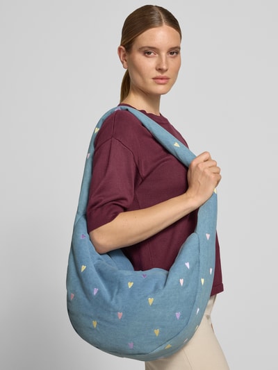 Frauenmodel trägt Shoulder Bag aus Baumwoll-Mix von Studio Noos in Blau mit bunten Herz-Stitchings, geräumiges Hauptfach, Nahaufnahme Oberkörper.