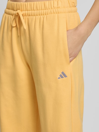 Kobiece modelka nosi Spodnie dresowe mit Logo und elastischem Bund od adidas Sportswear, mieszanka bawełny, krój regular fit, logo, elastyczny pas, tunel, długość wewnętrzna nogawki 79 cm w rozmiarze S, zbliżenie na górną część nogawki z przodu.