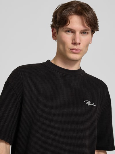 Männermodel trägt Oversized T-shirt mit structuurpatroon en labelstitching van Pegador in zwart, puur katoen, ronde hals, Nahaufnahme Oberkörper. Heren T-shirt, ruglengte bij maat M 70 cm, oversized fit.