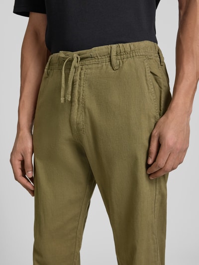 Männermodel trägt Relaxed Fit Hose aus Baumwoll-Leinen-Mix Modell 'KANE' von Jack & Jones, olivgrün, elastischer Bund mit Schnürung, Gesäßtaschen, Nahaufnahme Oberkörper. Herren Hose, Bundweite 42 cm, Innenbeinlänge 82 cm, glatte Textur.
