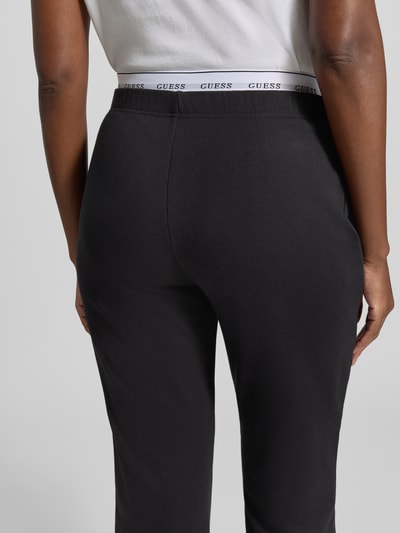 Vrouwenmodel draagt zwarte sweatpants met elastische band van GUESS, katoenmix, regular fit, Model 'SOFIA', detailopname, binnenbeenlengte maat S 76 cm.