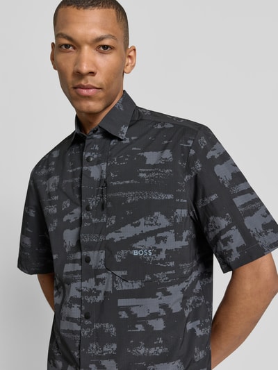 Männermodel trägt Relaxed Fit Freizeithemd mit Kentkragen Modell 'ST_GLOBE PRINT S' von BOSS Green, Allover-Muster, Nahaufnahme Oberkörper