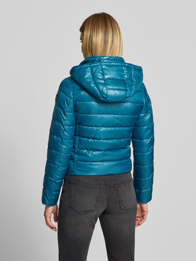 Frauenmodel trägt Regular Fit Jacke in Stepp-Optik von NAUTGÅRD, türkisblau, Kapuze, Reißverschluss, glatte Struktur, Ganzkörperansicht Rückansicht