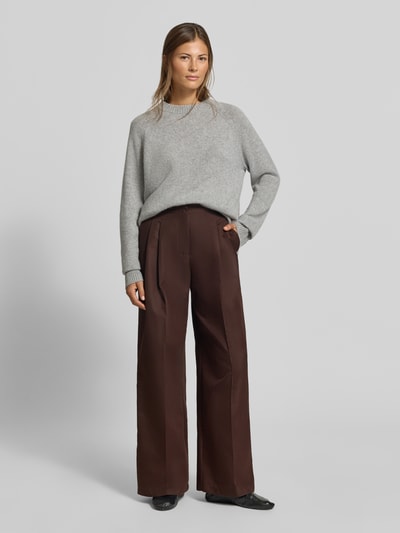 Frauenmodel trägt Relaxed Fit Stoffhose aus Baumwoll-Mix von MYON, Dunkelbraun, Kellerfalten, glatte Textur, Ganzkörperansicht von vorne.