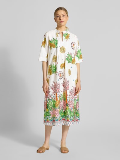 Frauenmodel trägt Midikleid mit V-Ausschnitt von Emily Van den Bergh, Reine Baumwolle, Gerader-Schnitt, 3/4-Arm, Seitenschlitz, florales Muster, Ganzkörperansicht von vorne.