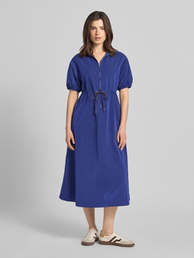 Frauenmodel trägt Midikleid mit kurzem Reißverschluss und Kordelzug an der Taille von Rich & Royal in Blau, taillierter Schnitt, gerippter Kentkragen, halblange Ärmel mit elastischen Abschlüssen, glatte Stoffstruktur, Ganzkörperansicht von vorne.