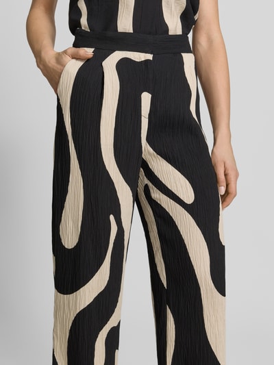 Frauenmodel trägt Stoffhose aus Viskose-Mix im Allover-Look Modell 'NIKITA' von Mango, Relaxed-Fit, Nahaufnahme Oberkörper, Damen. Bundweite bei Größe 36: 41 cm, Innenbeinlänge bei Größe 36: 77 cm.