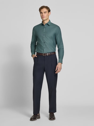 Männermodel trägt Modern Fit Businesshemd aus reiner Baumwolle von OLYMP in Grün, kombiniert mit dunkler Hose, Ganzkörperansicht von vorne, Herren Businesshemd von OLYMP.