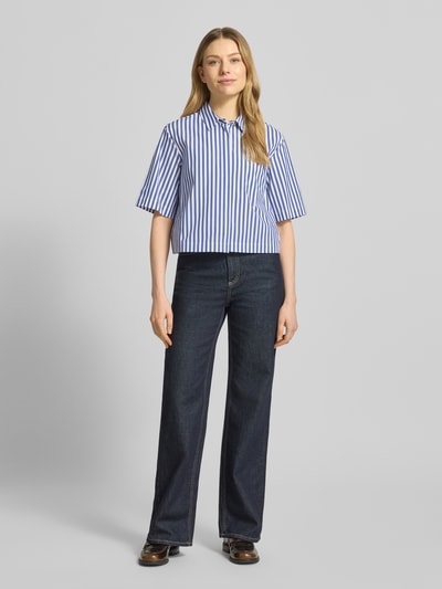 Modelka nosi Regular Fit Hemdbluse mit Umlegekragen Modell 'Bette' od JOOP!, niebiesko-białe pasy, bawełniana mieszanka, półrękaw, widok całej sylwetki z przodu.