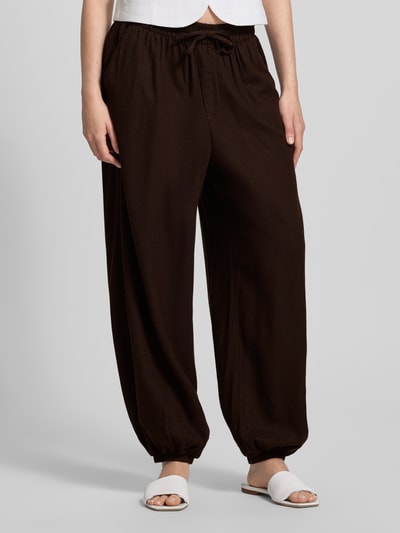 Frauenmodel trägt Regular Fit Weite Hose aus Viskose-Leinen-Mix Modell 'GOA' von Only, Optik: Unifarben, Materialverarbeitung: Flammgarn, Tunnelzug, Bundabschluss und Beinabschluss elastisch, seitliche Eingrifftaschen und Gesäßtasche, Farbe Braun, Nahaufnahme Unterkörper.