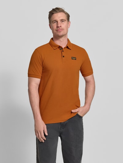 Męskimodel nosi Slim Fit Poloshirt mit Logo-Patch von PME Legend, mieszanka bawełny, krój slim fit, kołnierzyk polo, krótki rękaw, długość tyłu w rozmiarze M: 70 cm, widok całej sylwetki z przodu.