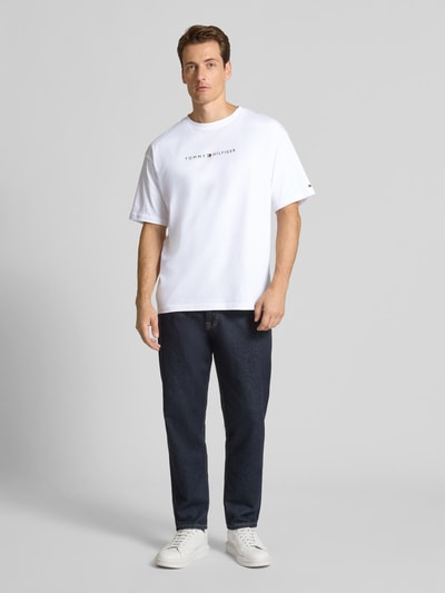 Männermodel trägt Relaxed Fit T-Shirt aus reiner Baumwolle von Tommy Hilfiger in Weiß mit Logo-Stitching, Rundhalsausschnitt, Ganzkörperansicht von vorne.