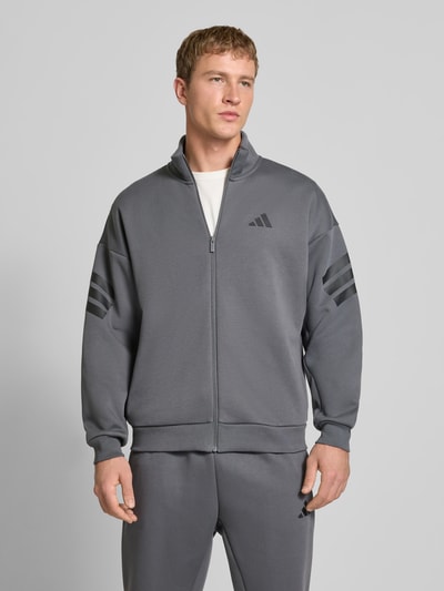 Männermodel trägt Sweatjacke mit Logo und Reißverschluss von adidas Sportswear, grau, Regular Fit, Materialmix mit Baumwolle, Nahaufnahme Oberkörper.