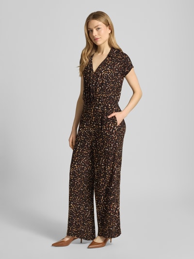 Modelka nosi Jumpsuit aus Viskose Modell 'MARRAKECH' od ICHI, czarna tkanina z kolorowym wzorem, krój regular fit, kołnierzyk, dekolt V, długość całkowita w rozmiarze S 136 cm, szerokość w rozmiarze S 47 cm, długość pleców w rozmiarze S 137 cm, długość nogawek w rozmiarze S 68 cm, widok całej sylwetki z przodu.