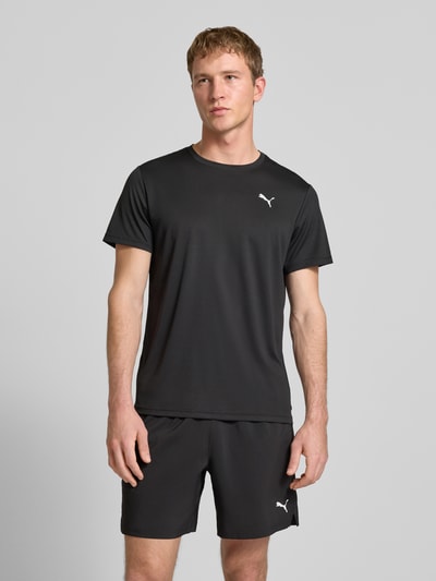 Männermodel trägt schwarzes T-Shirt mit Label-Print von PUMA PERFORMANCE, Regular Fit, Rundhalsausschnitt, Ganzkörperansicht von vorne.