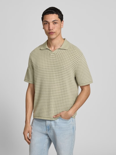 Männermodel trägt Regular Fit Poloshirt mit V-Ausschnitt von Jack & Jones aus reiner Baumwolle, Strickshirt in hellem Grün kariert, Nahaufnahme Oberkörper.