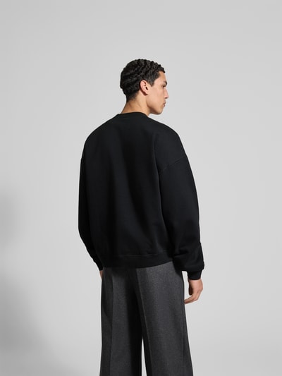 Männermodel trägt Sweatshirt aus reiner Baumwolle von Dsquared2 in Schwarz, Relaxed-Fit, Stehkragen, Label-Detail, elastische Abschlüsse, Rückenlänge bei Größe M 67 cm, Ganzkörperansicht Rückansicht.