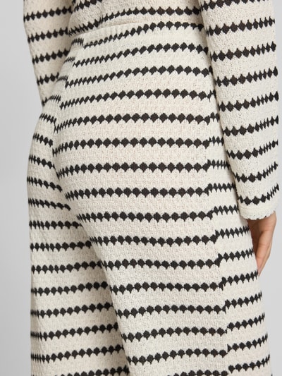 Frauenmodel trägt Loose Fit Stoffhose mit Baumwoll-Anteil Modell 'EVA LIFE' von Only mit schwarz-weißem Allover-Muster, Nahaufnahme Hüfte.