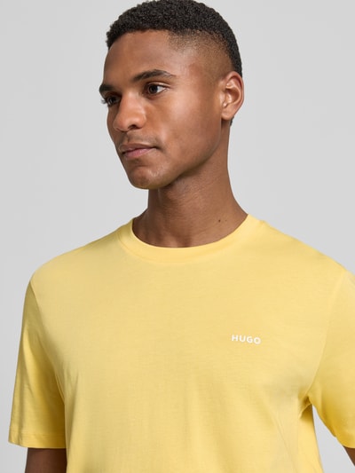 Männermodel trägt Regular Fit T-Shirt aus reiner Baumwolle Modell 'DERO222' von HUGO, Optik: Unifarben, Label-Print, Rundhals, Kurzarm, Jersey, Nahaufnahme Oberkörper.