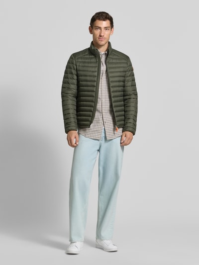 Männermodel trägt olivgrüne Steppjacke mit Zweiwege-Reißverschluss Modell 'ALEXANDER' von Save The Duck, Stehkragen, Ganzkörperansicht von vorne. Slim Fit, Reißverschlusstaschen, Rückenlänge 67 cm, Schulterbreite 47 cm, Brustweite 57 cm, Ärmellänge 68 cm.