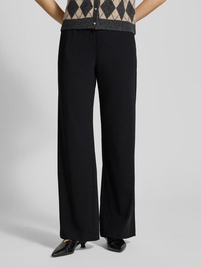 Frauenmodel trägt Stoffhose mit elastischem Bund Modell 'Christy' von MAC, Material-Mix mit Stretch-Anteil, lockerer Schnitt, Seitentaschen, schwarz, Nahaufnahme Unterkörper, Aufnahme von vorne.
