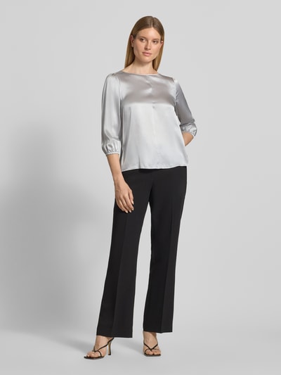 Modelka nosi Blusenshirt aus Seide mit 3/4-Arm od Marc Cain w kolorze srebrnym, krój regular fit, okrągły dekolt, długość tyłu 60 cm, długość rękawów 49 cm, widok całej sylwetki z przodu.