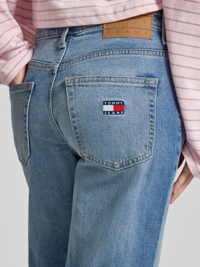 Frauenmodel trägt Straight Fit Jeans aus Baumwoll-Mix Modell 'SOPHIE' von Tommy Jeans in Denim-Optik mit Label-Patch, Logo-Stitching, 5-Pocket-Design, und Gürtelschlaufen, Materialverarbeitung Twill, Detailaufnahme der Rückansicht.