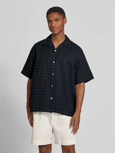 Männermodel trägt Relaxed Fit Freizeithemd aus reiner Baumwolle Modell 'MONTY' von SELECTED HOMME in Schwarz, Jacquard-Struktur, Ganzkörperansicht von vorne.