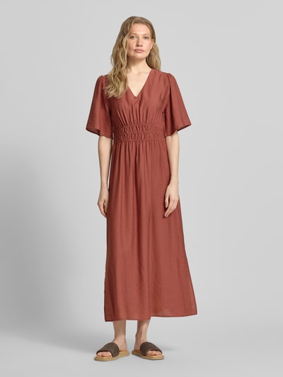 Frauenmodel trägt Maxikleid aus Viskose-Mix mit V-Ausschnitt Modell 'Iggy' von B.Young in Rostrot mit Falten-Optik, Ganzkörperansicht von vorne, taillierte Passform, Halbarm, Rückenlänge bei Größe 36: 131 cm, Brustweite: 34 cm, Ärmellänge: 31 cm.