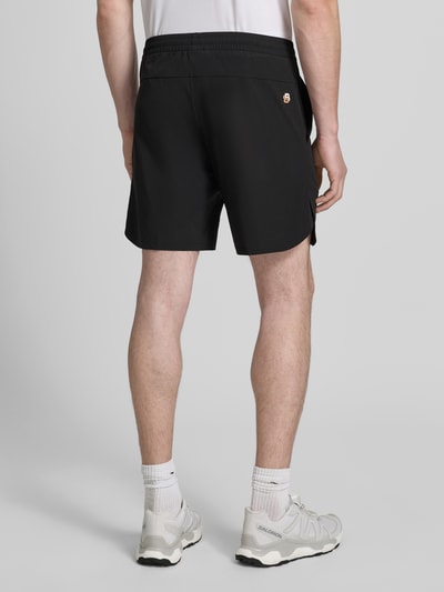 Mężczyzna nosi czarne spodenki o kroju regular fit Regular Fit Sportshorts mit Logo-Details model 'SH_TOC GAME 8 INCH' od BOSS Green, gładka tekstura, widok całej sylwetki z tyłu.