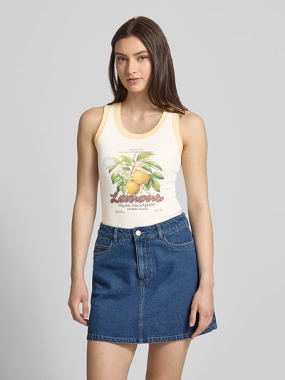 Vrouwenmodel draagt Trägertop mit Motiv-Print Modell 'HILDA' van JJXX, katoen-elastaan-mix, slim fit, ronde hals, witte en gele tinten, motiefprint fruit, gecombineerd met een blauwe denim rok, voorkant volledig zichtbaar, Ganzkörperansicht von vorne.