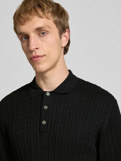 Männermodel trägt Slim Fit Strick-Poloshirt mit Zopfmuster Modell 'EMIL' von Jack & Jones, Baumwoll-Mix, Nahaufnahme Oberkörper.