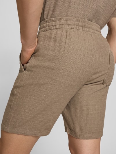 Männermodel trägt Regular Fit Shorts aus Viskose-Leinen-Mix Modell 'TEL LATHAM' von Only & Sons, beige, strukturierte Oberfläche, Nahaufnahme Rückansicht.