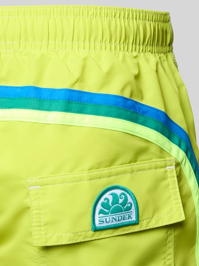 Produktfoto, Badehose mit elastischem Bund Modell 'UNI SHORTS NEON' von Sundek in leuchtendem Gelb mit grünen und blauen Streifen, Regular-Fit, Tunnelzug, glatte Textur