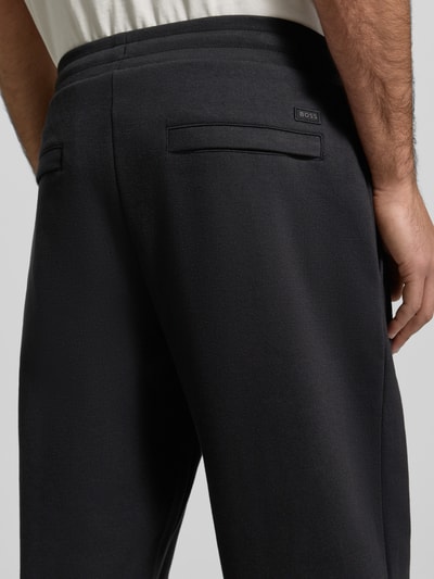 Männermodel trägt Relaxed Fit Sweatpants aus Baumwoll-Mix Modell 'SE_TWIST' von BOSS Orange, jednokolorowy melanż, naszywka z logo, zakładka w pasie, zamek błyskawiczny, elastyczny ściągacz, tunel, kieszenie z tyłu na zamek i wpuszczane, wykończenie materiału: dzianina dresowa, mieszanka bawełny, detal: tylna perspektywa, zbliżenie na górną partię.