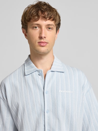 Männermodel draagt Relaxed Fit vrijetijdsoverhemd met labelstitching model 'Forno' van Pegador, puur katoen, all-over look, kentkraag, knoopsluiting, kleur lichtblauw met witte strepen, textuur met fijne ribbels, Nahaufnahme Oberkörper.