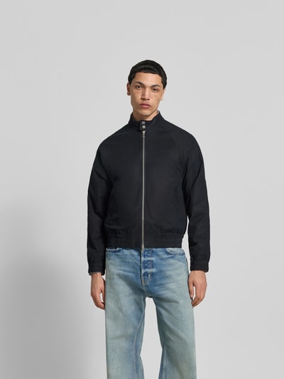 Männermodel trägt Bomberjacke aus Baumwoll-Mix von Officine Générale in Schwarz, Zweiwege-Reißverschluss, Gerade Passform, Raglanärmel, elastische Abschlüsse, Rückenlänge 55 cm, Schulterbreite 45 cm, Ärmellänge 63 cm, Ganzkörperansicht von vorne.