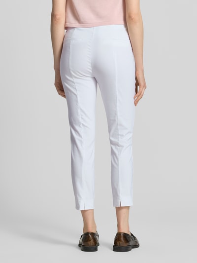Frauenmodel trägt Slim Fit Stoffhose in verkürzter Passform von Christian Berg Woman in Weiß, glatte Textur, ganzkörperansicht Rückansicht. Elastischer Baumwoll-Mix, Knopf- und Reißverschluss, Produktdetails laut Kontext.