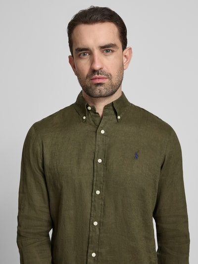 Männermodel trägt Regular Fit Freizeithemd aus reinem Leinen von Polo Ralph Lauren, Optik: Unifarben, Materialverarbeitung: Flammgarn, Knopfleiste, Button-Down-Kragen, Logo-Detail, Langarm, Nahaufnahme Oberkörper.