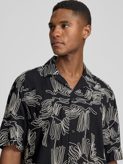 Männermodel trägt Freizeithemd mit floralem Allover-Stitching Modell 'Liam' von Les Deux, schwarzer Baumwoll-Mix, Nahaufnahme Oberkörper.